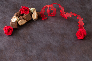 バレンタイン・イメージ　チョコレートと赤いプリザーブドフラワーのバラとハートのリボン（茶色の背景）