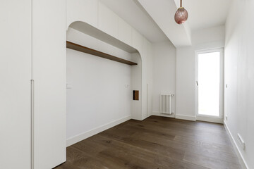 A bedroom with a decorative structure and built-in wooden wardrobes