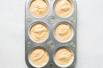 almond muffins batter in a cupcake pan, almond muffins topped with sliced almonds, process of making almond muffins