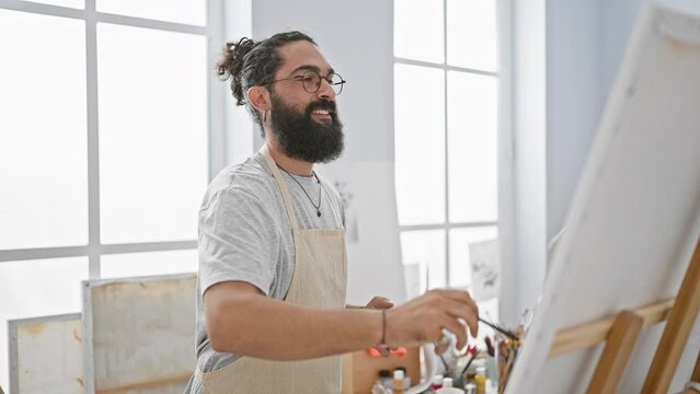 Happy bearded man painting in a bright art studio, showcasing creativity and casual style.