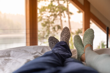 Happy couple feet relax in bed at home with cozy warm socks on enjoying weekend winter holiday 