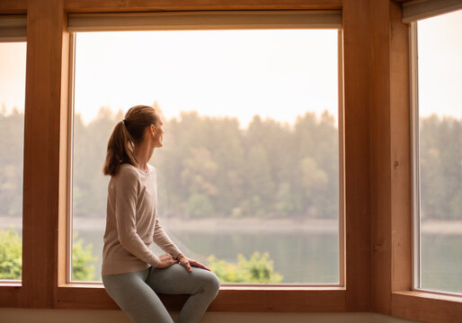Young woman looking out window early morning 