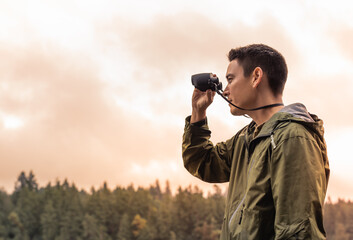 Young man exploring the wilderness travel adventure  looking through binoculars
