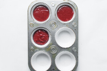 Top view of Red velvet cupcake batter in a lined muffin tin, process of making valentines cupcakes