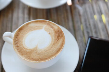 Hot latte in a white glass on a bamboo table