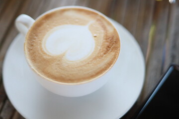 Hot latte in a white glass on a bamboo table