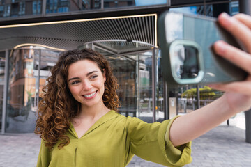 Business woman taking selfie photo using smart phone app on smartphone for social media. Young businesswoman using smartphone smiling happy.