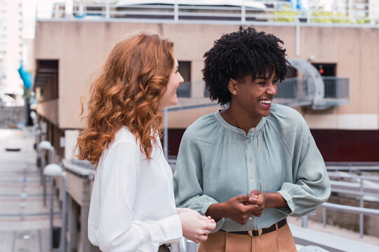 Two Trendy Businesswomen Talking And Laughing Casually Outside