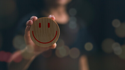 A woman holding a smiley face on a wooden board with a bokeh background. good feedback rating,...