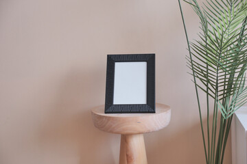  empty photo frame on table against white light orange color wall 