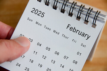 Close up view of February 2025 Calendar on wooden desk background. Monthly calendar concept.