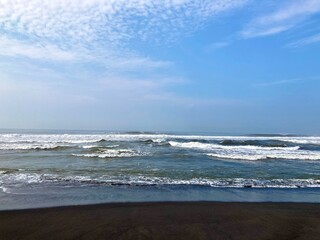 sea waves on a beach with black sand, holiday and vacation at summer