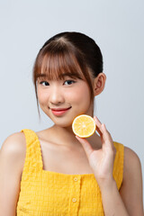 Woman holds cut juicy fruit near face skin.