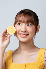 Woman holds cut juicy fruit near face skin.