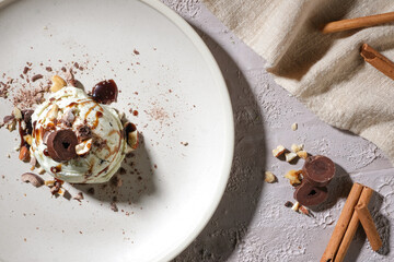 Flat lay of an ice cream ball on a round ceramic plate with nut and chocolate chips, on a...