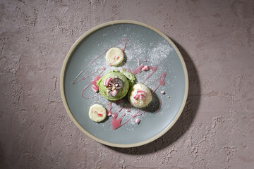 The ice cream balls are decorated with strawberry sauce on a decorative ceramic plate. The minimalist rough concrete background highlights the appeal of the dessert.