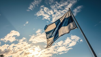 Finnish flag fluttering against a sunny blue sky with clouds