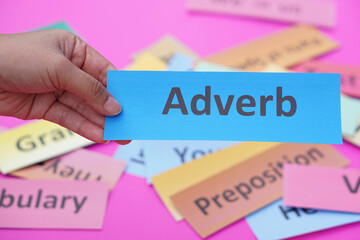 Close up hand hold blue word card with text Adverb. Concept, English language grammar teaching. Using word card to create for playing educational fun games. Part of speech                    