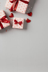 Fototapeta na wymiar Vertical banner design for Valentines Day. Flat lay gift boxes with red ribbon bows and heart shaped candy on gray table. Valentines Day background. Flat lay, top view.