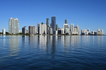 City of Miami, Florida skyline reflected in calm water of Biscayne Bay on calm cloudless December morning.
