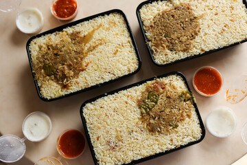 Women hand eating Mutton biryani. Packed box take away Chicken biryani Indian Malabar Kozhikode Hyderabadi biryani pulao Kerala India Pakistan basmati rice mixed rice dish meat curry Ramadan Eid