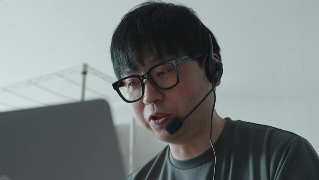Asian male doing call center work / work from home