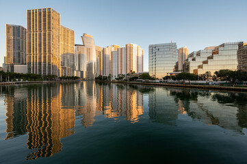 Obraz premium City of Miami, Florida skyline reflected in calm water of Biscayne Bay at sunrise on clear cloudless December morning.