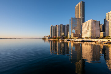 Obraz premium City of Miami, Florida skyline reflected in calm water of Biscayne Bay at sunrise on clear cloudless December morning.