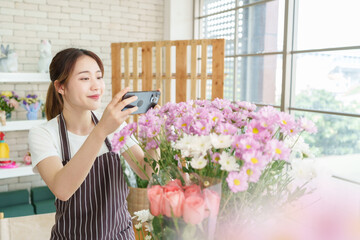 Chinese woman florist taking photo of bouquet of flowers with smartphone