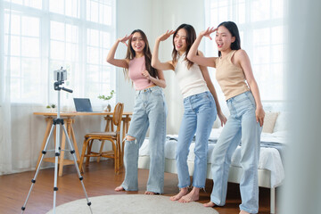 Asian Chinese female friends dancing in front of a mobile phone.