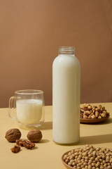 Wooden dishes of soybeans, cashew nuts and walnuts displayed on beige surface with containers of milk. Nuts are a great source of several nutrients, including vitamin E
