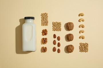 Flat lay of an unbranded milk bottle arranged with four lines of soybeans, walnuts, almond and...
