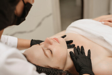 close-up of a woman's cosmetologist's hands massaging the client's facial skin. The concept of a cosmetic procedure.