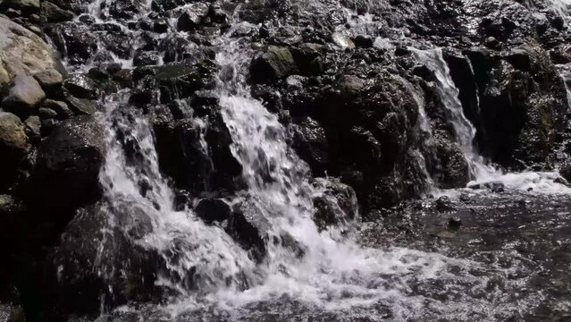 mini waterfall water flows fast between rocks in slowmotion