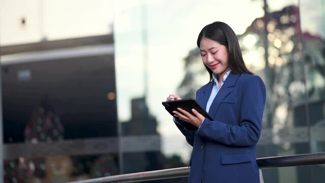 Young Asian business woman leader entrepreneur, professional manager holding digital tablet computer uon the street in big city