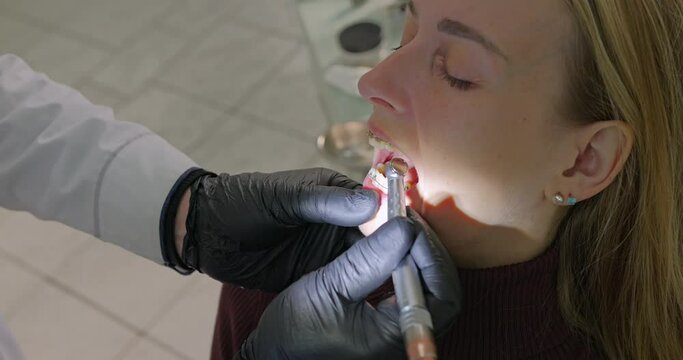 Young woman with braces gets treatment in the dental office. 