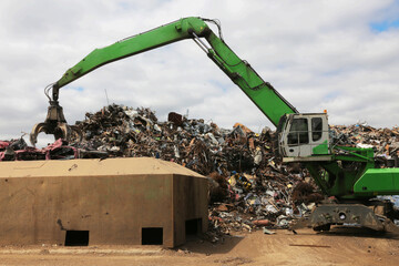 A jaw crane puts scrap metal into a crusher for raw materials.