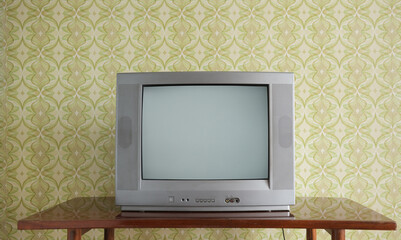 Old TV on the nightstand against the background of wallpaper.