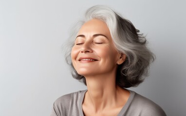 Smiling elderly woman with closing eyes makes yoga