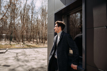 The image depicts a person wearing a suit standing outdoors in front of a
