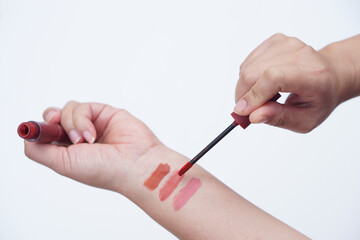 Close up woman hand is testing lip gloss different colors, apply on her arm. Lipstick swatches on hand for colors test or cosmetic allergy test. Make up equipment or tool.     
