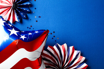 American flag balloon, paper fans, confetti on dark blue table. USA Independence Day background,...