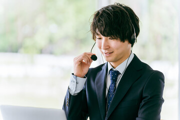 ヘッドセットをつけてパソコンを使う男性

