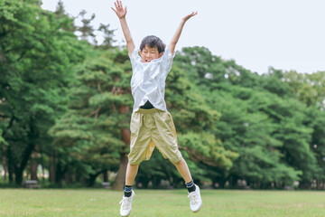 公園・キャンプ場でジャンプする小学生の男の子
