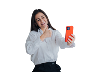 Pretty cheerful caucasian young woman makes video call using phone broad smiles gestures thumb up against transparent background. Brunette female student talks with parents with parents.