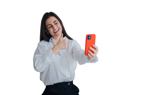Pretty cheerful caucasian young woman makes video call using phone broad smiles gestures thumb up against transparent background. Brunette female student talks with parents with parents. - Powered by Adobe