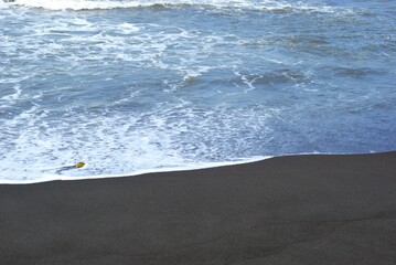 sea waves on a beach with black sand, holiday and vacation at summer