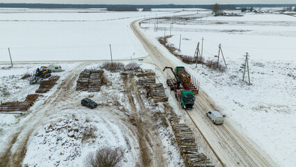 Drone photography of log lorry piking up logs during winter day