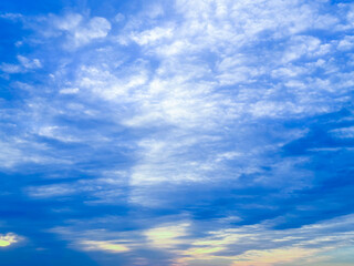 大きな海に波が打ち寄せ、青い大空と太陽と夕日が混ざり合い、高台から見下ろす実写写真