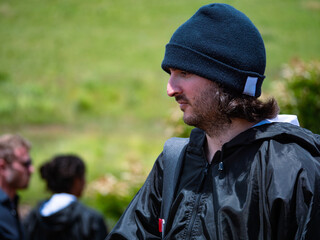 Homme vue de profil, voyageant avec un bonnet et un imperméable en saison froide avec un paysage...